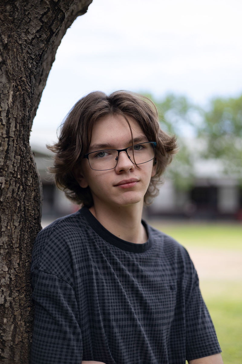 Brandon leaning against a tree