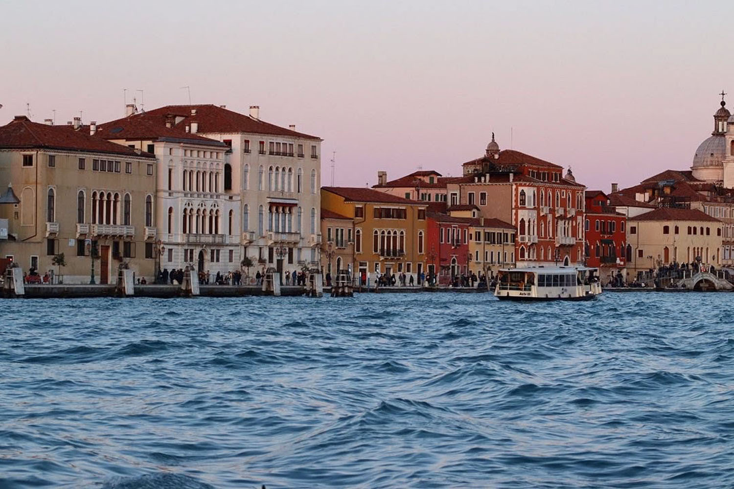 Boat on the water in front of a row of homes