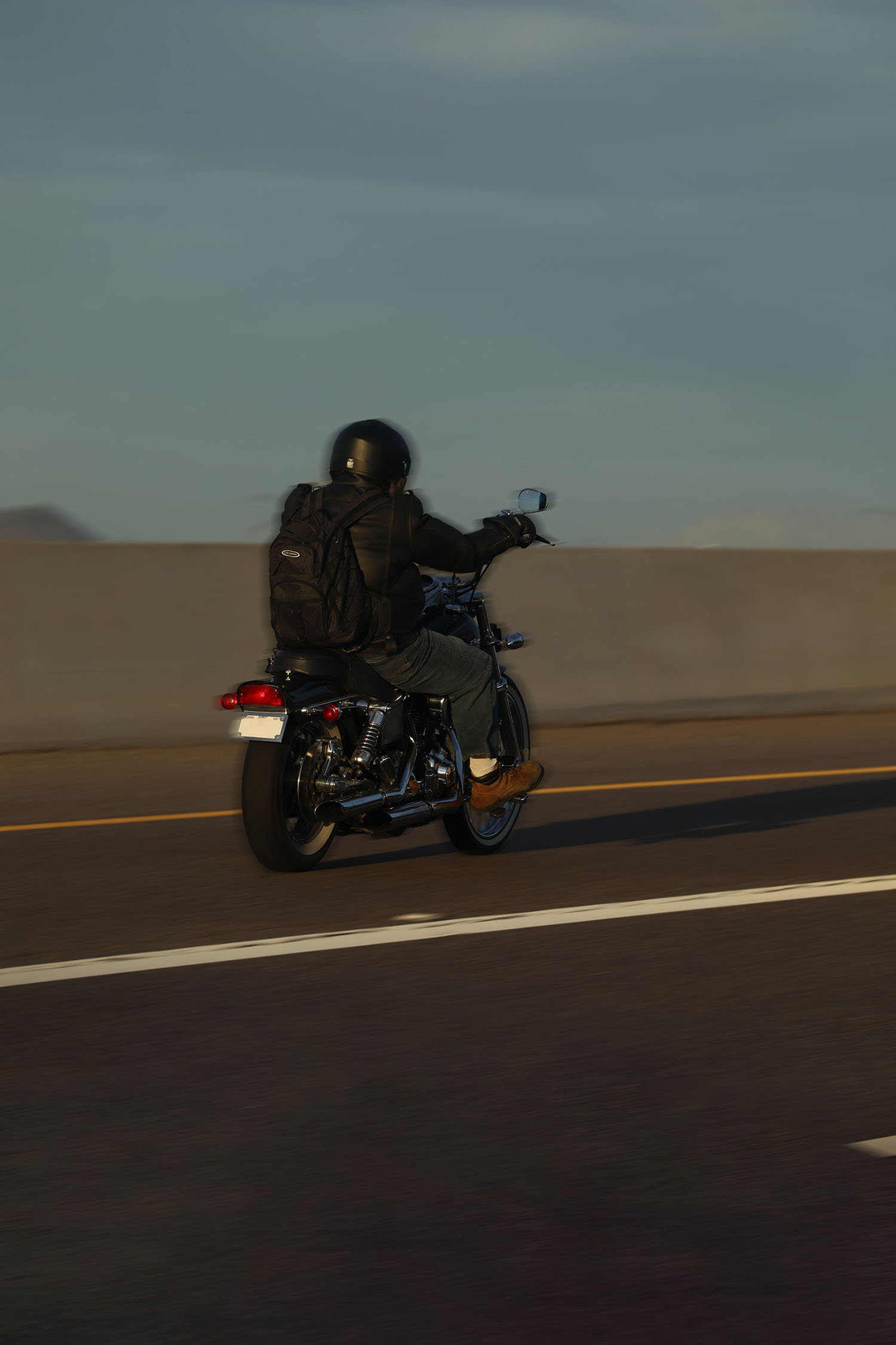 Motorcycist riding down the highway with his back to us