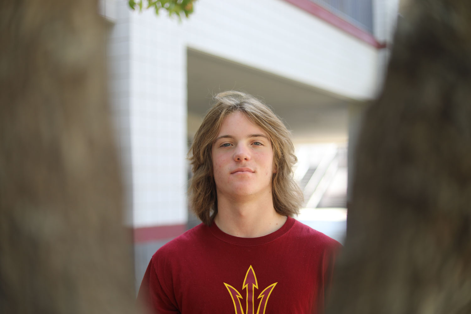 Student looking at the camera between the tree limbs