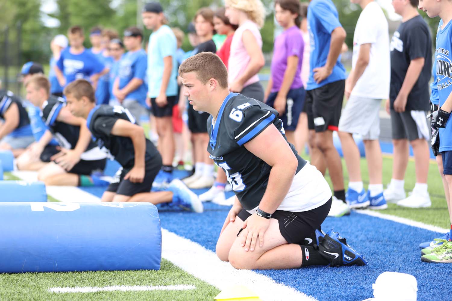 Football player showing younger kids a drill