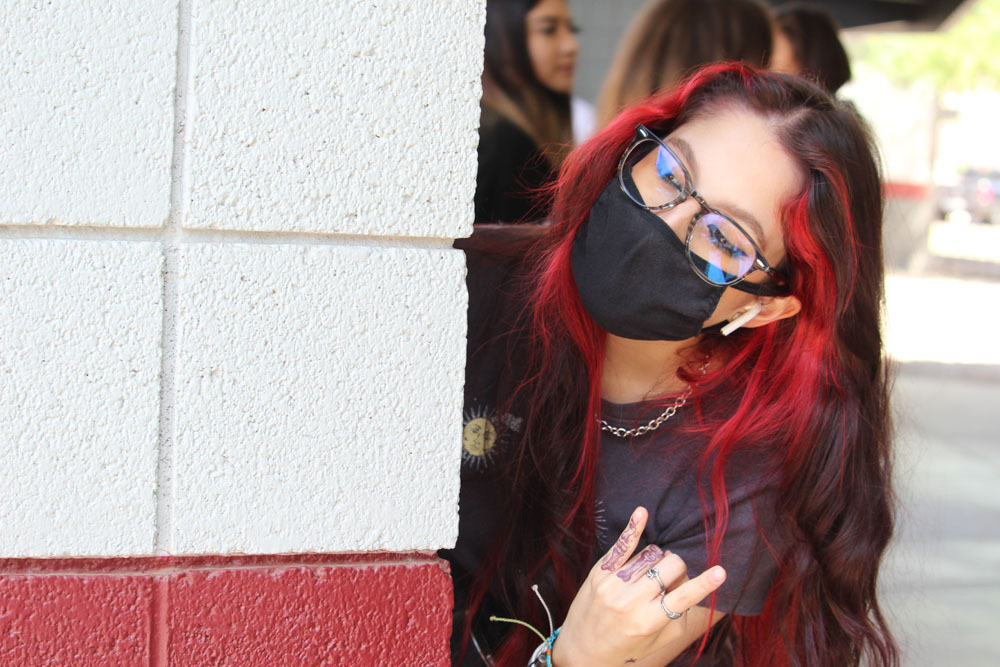 Person Behind A Wall Showing Rock Sign