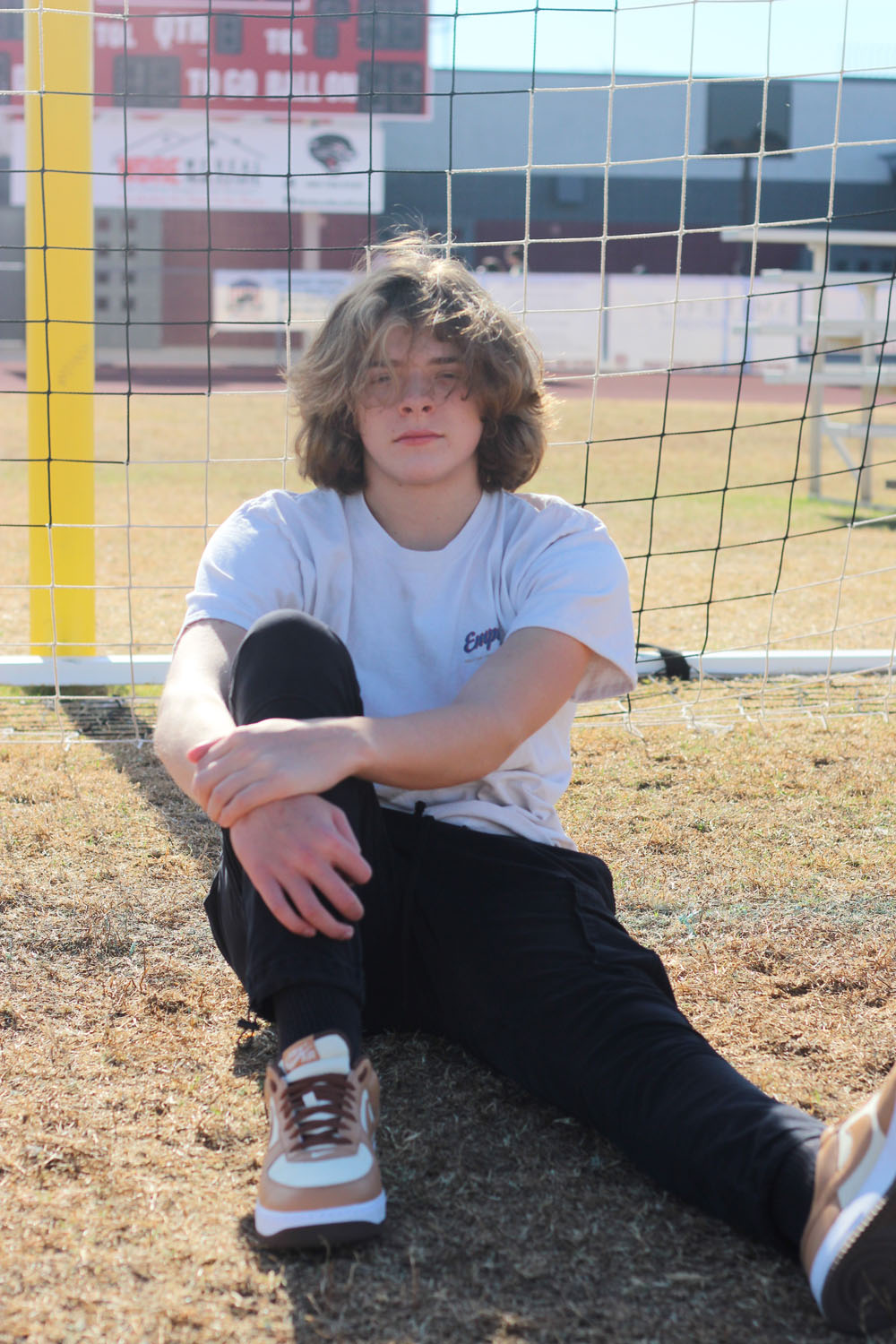 Alex sitting down in front of soccer goal