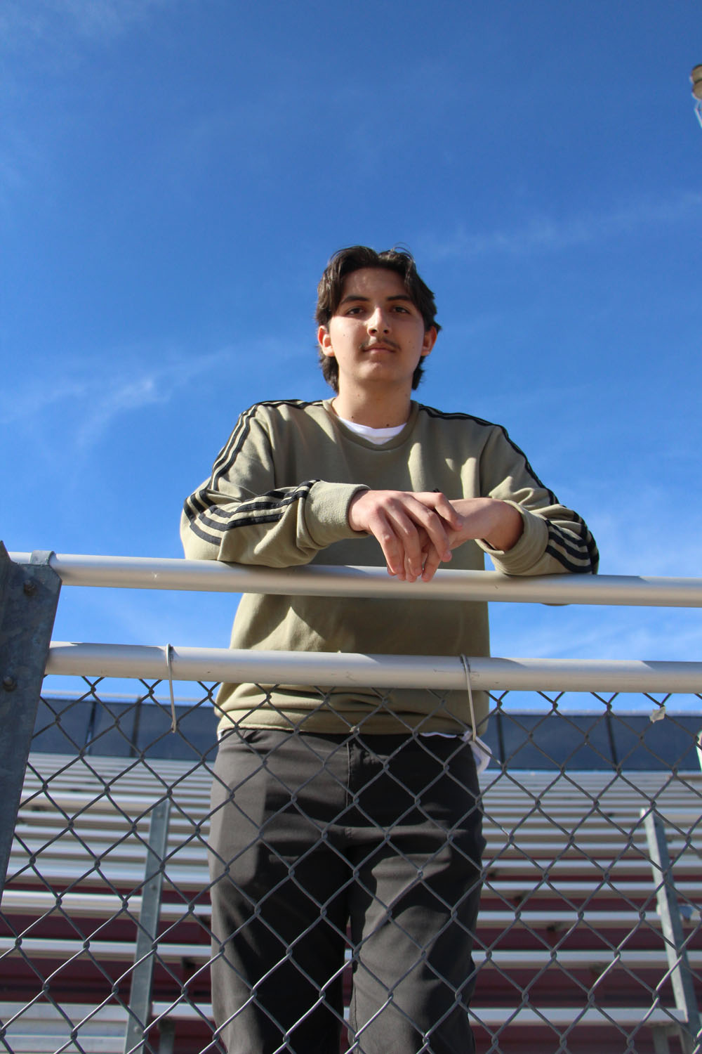 A guy leaning on a fence