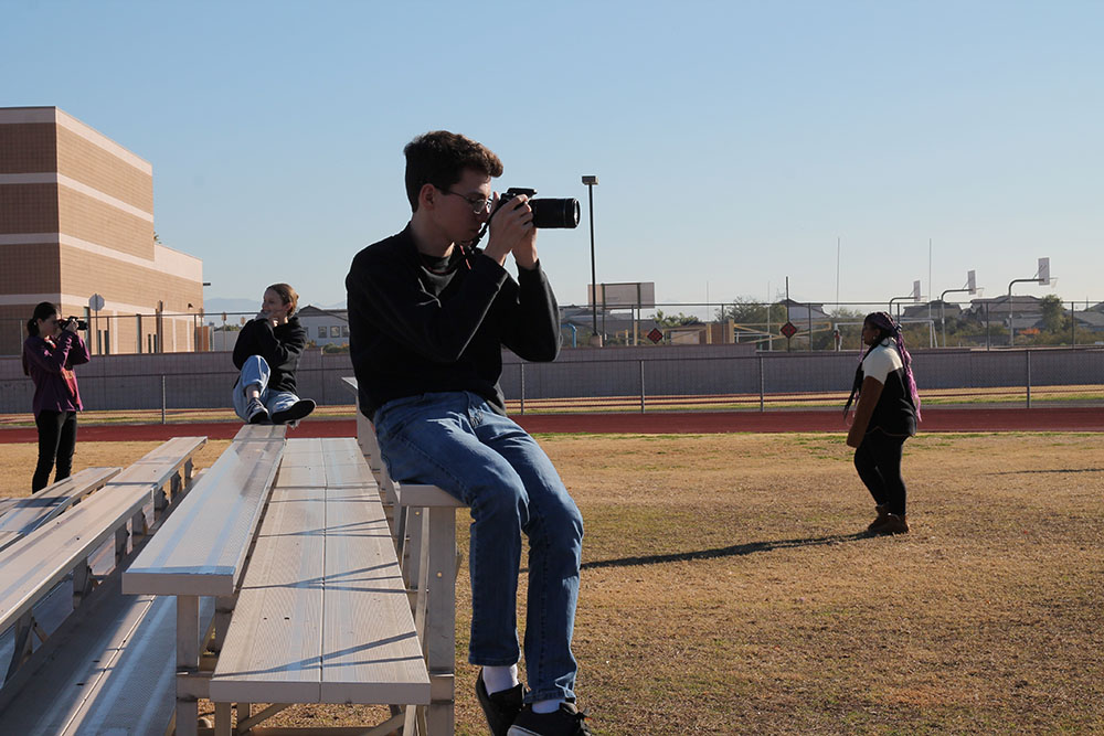 Grant sitting on a bench taking pictures