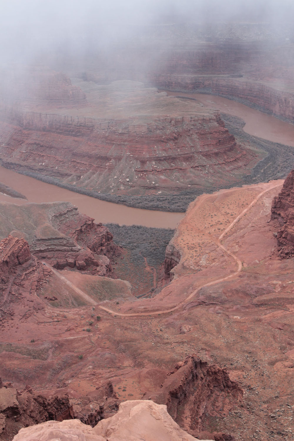 A canyon with a river running through it on a foggy day.