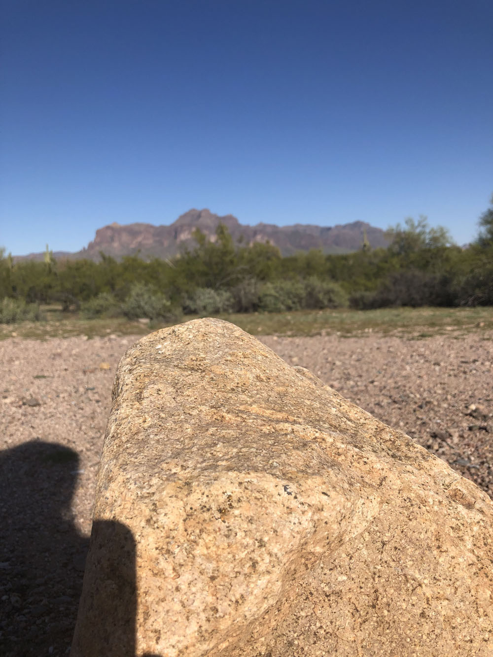 A rock as the foreground and the superstition mountains in the background